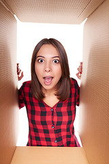 Image showing Girl opening a carton box and looking inside