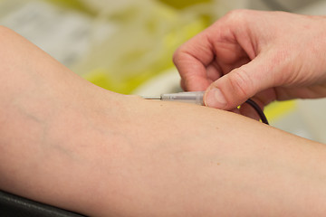 Image showing Donor in an armchair donates blood, inserting the needle