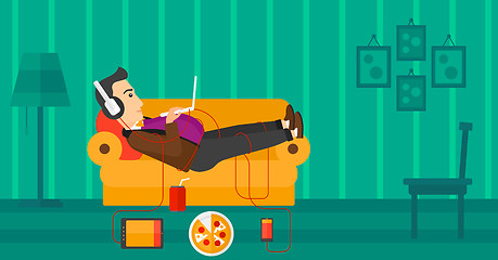 Image showing Man lying on sofa with many gadgets.