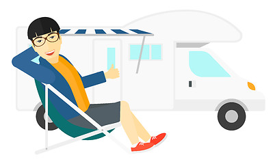 Image showing Man sitting in front of motorhome.