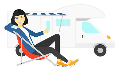 Image showing Woman sitting in front of motorhome.