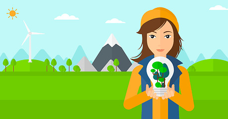 Image showing Woman with lightbulb and trees inside.