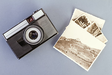 Image showing Vintage photo camera and old photos on a gray table