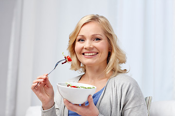 Image showing smiling middle aged woman eating salad at home