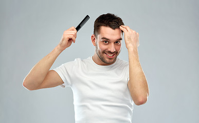 Image showing happy man brushing hair with comb over gray