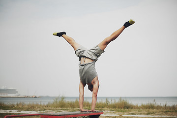 Image showing young man exercising on bench outdoors