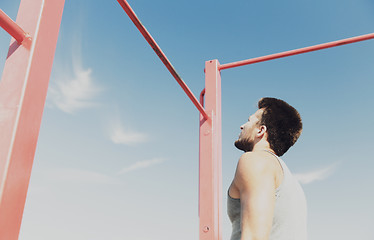 Image showing young man exercising on horizontal bar outdoors