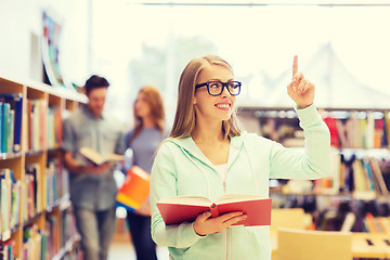 Image showing happy student girl or woman with book in library