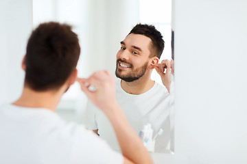 Image showing man cleaning ear with cotton swab at bathroom