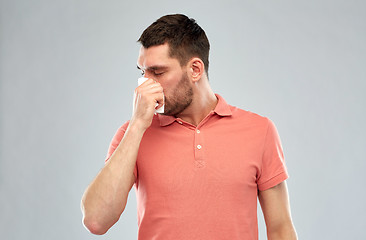 Image showing sick man with paper napkin blowing nose