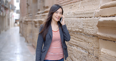 Image showing Young woman walking through town with her mobile