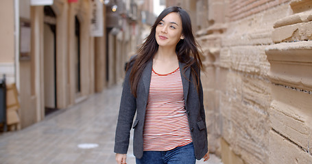 Image showing Young woman walking through an alley in town