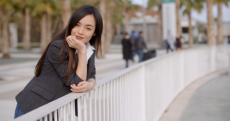 Image showing Young thoughtful woman leaning on a railing