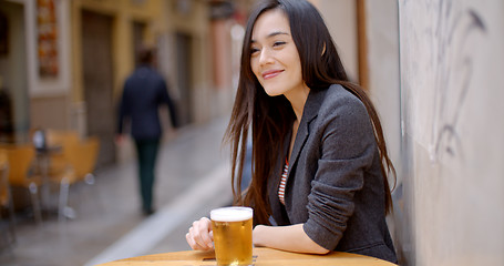Image showing Friendly young woman sitting enjoying a beer