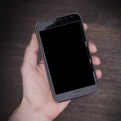 Image showing Hand with smart phone on wooden table