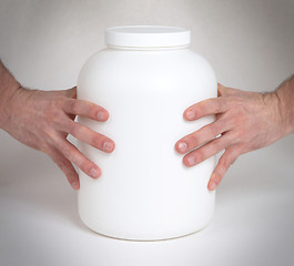 Image showing Bodybuilding and Sports themehands holding a plastic jar with a 