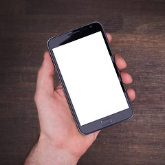 Image showing Hand with smart phone on wooden table