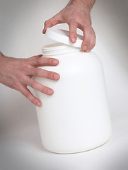 Image showing Bodybuilding and Sports themehands holding a plastic jar with a 