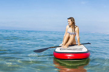 Image showing Woman sitting over a paddle surfboard