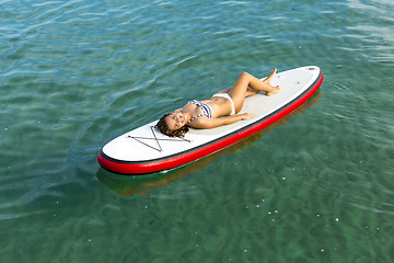 Image showing Woman relaxing over a paddle surfboard