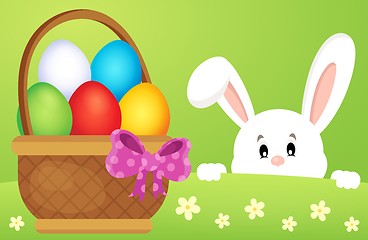 Image showing Lurking Easter bunny by basket with eggs