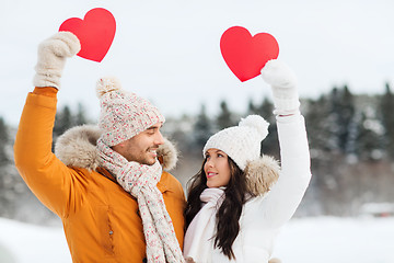 Image showing happy couple with red hearts over winter landscape