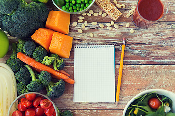 Image showing close up of ripe vegetables and notebook on table