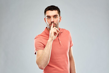 Image showing young man making hush sign over gray background