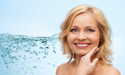 Image showing smiling woman with bare shoulders touching face