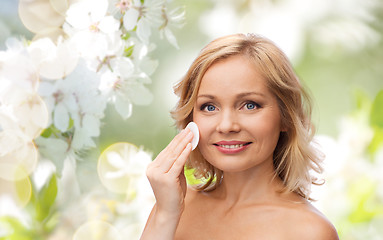 Image showing happy woman cleaning face with cotton pad