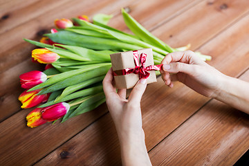Image showing close up of woman with gift box and tulip flowers