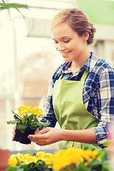 Image showing happy woman holding flowers in greenhouse