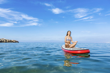 Image showing Woman relaxing over a paddle surfboard