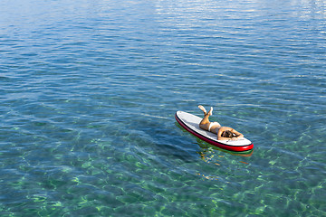 Image showing Woman relaxing over a paddle surfboard