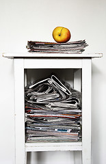 Image showing stack of newspapers on the nightstand and an apple