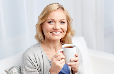 Image showing smiling woman with cup of tea or coffee at home