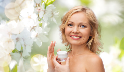 Image showing happy woman applying cream to her face