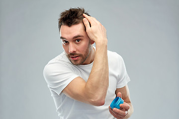 Image showing happy young man styling his hair with wax or gel