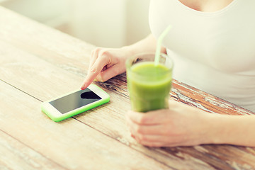 Image showing close up of woman with smartphone and green juice