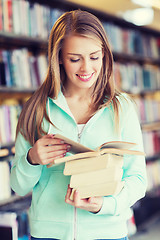 Image showing happy student girl or woman with book in library