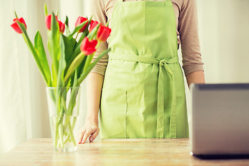 Image showing close up of woman with tulips in vase and laptop