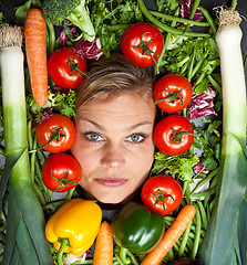 Image showing Cute blond girl shot in studio with vegetables aroound the head