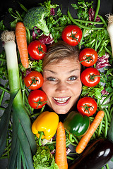 Image showing Cute blond girl shot in studio with vegetables aroound the head