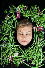 Image showing Cute blond girl shot in studio with vegetables aroound the head