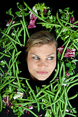 Image showing Cute blond girl shot in studio with vegetables aroound the head