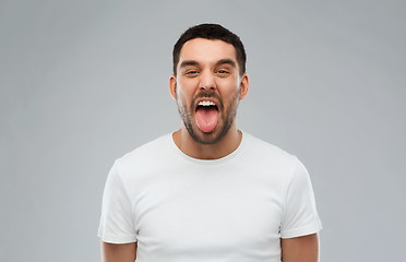 Image showing man showing his tongue over gray background