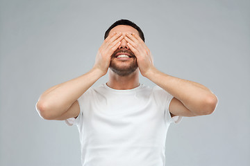 Image showing smiling man closing his eyes over gray background