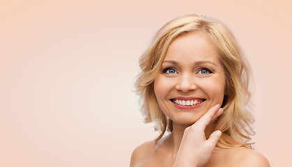 Image showing smiling woman with bare shoulders touching face