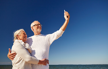 Image showing seniors with smartphone taking selfie on beach