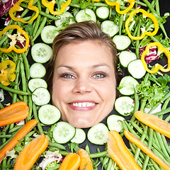 Image showing Cute blond girl shot in studio with vegetables aroound the head